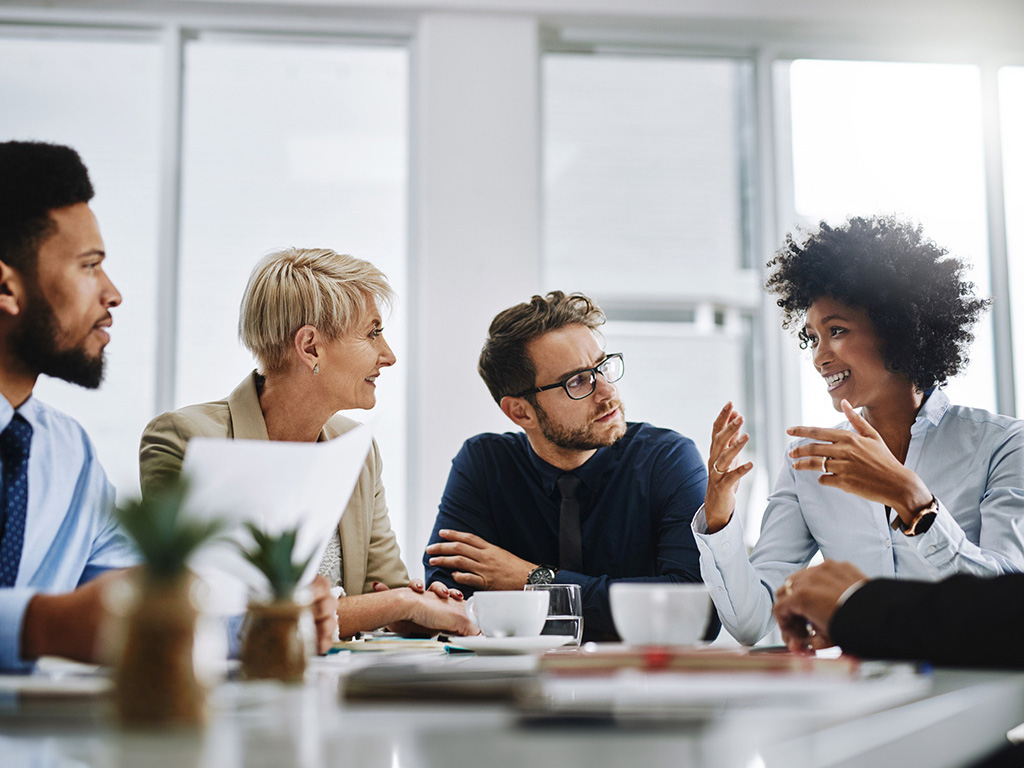 Gruppo di professionisti aziendali che ascolta i consigli di una consulente esperta.