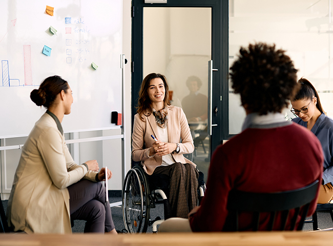 Gruppo di persone di background diversi e con disabilità che progetta insieme in una sala riunioni.