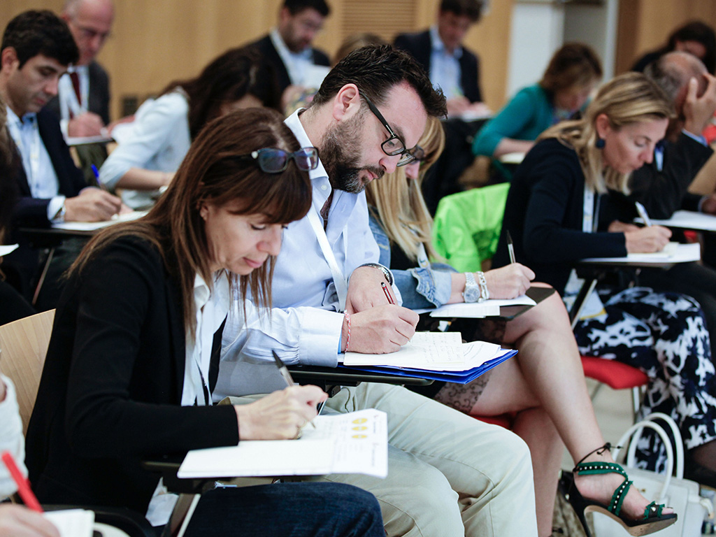 Primo piano di persone che prendono appunti durante un corso di formazione in presenza.