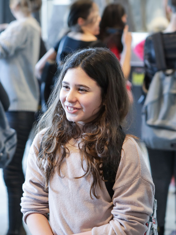 Primo piano di una studentessa della scuola secondaria di primo grado che sorride all’interno di una scuole con altri studenti.