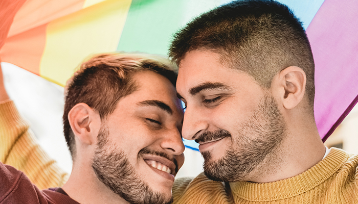 Primo piano di una coppia LGBTQIA+ che si guarda e sorride.