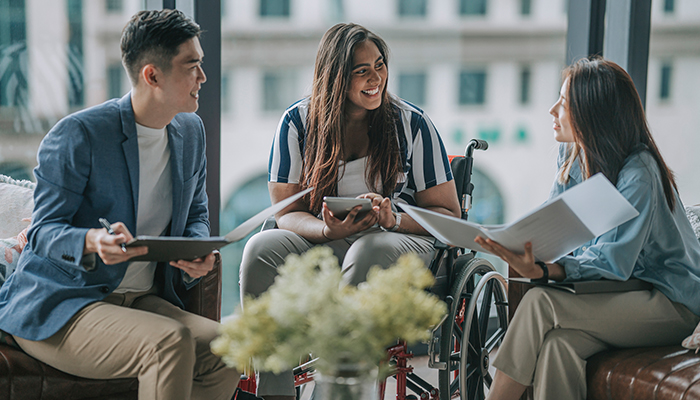 Gruppo di persone con background diversi e con disabilità che si confronta all’interno di spazi aziendali.​