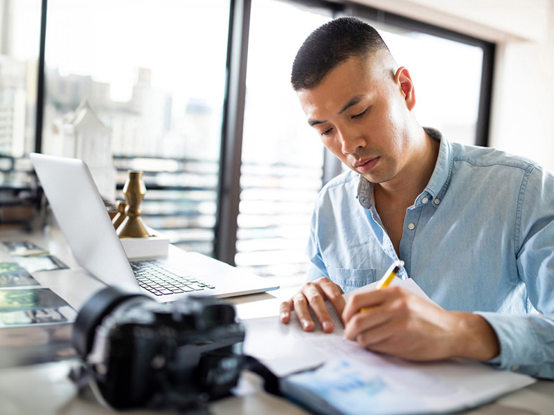 Primo piano di un professionista impegnato a scrivere alla scrivania.