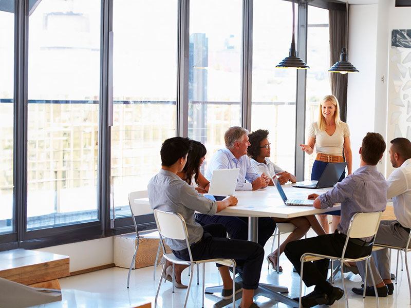 Gruppo di persone di background diversi che partecipa a una riunione di lavoro, confrontandosi e lavorando insieme.