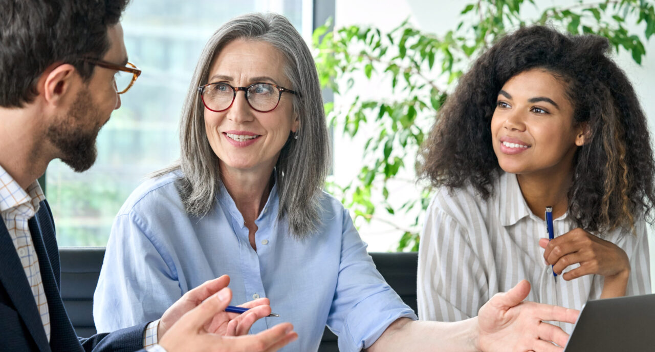 Due donne di diverse età e un uomo conversano al lavoro