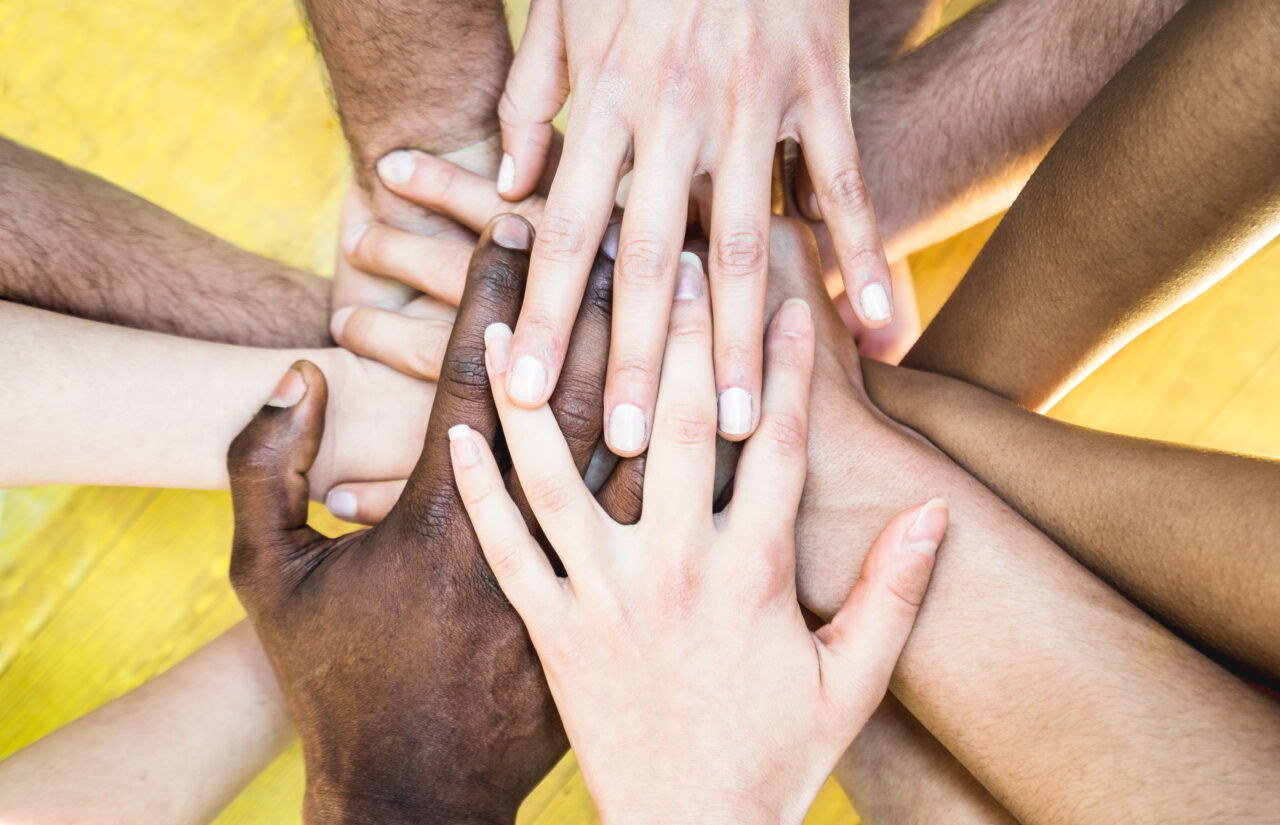 Mani di persone di diverse etnie che si sovrappongono